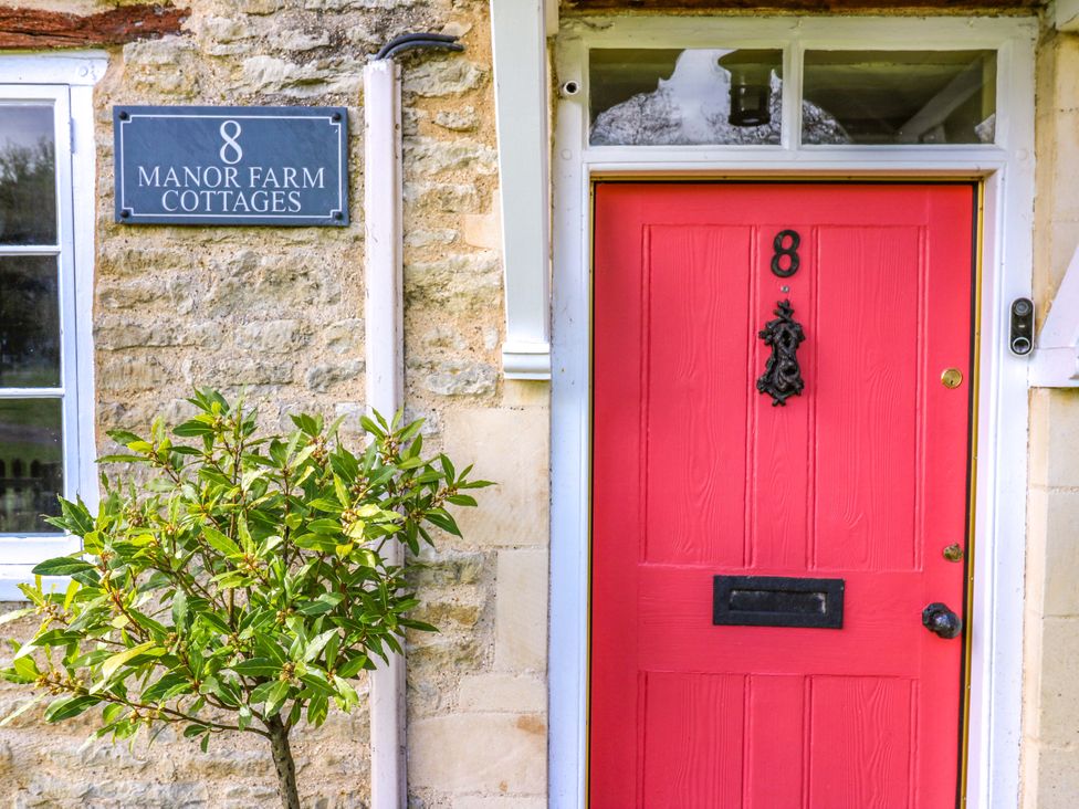 An entrance with a red door and a nameplate at Manor Farm Cottages in Loughton, Milton Keynes