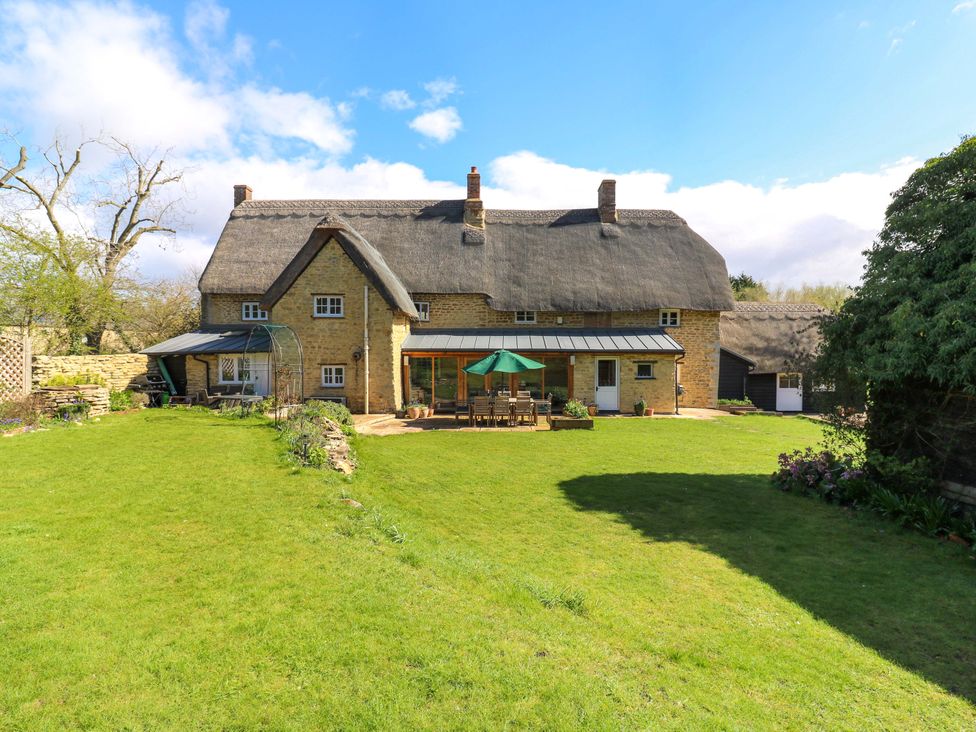 A house with a thatched roof and garden at Manor Farm Cottages Loughton Milton Keynes