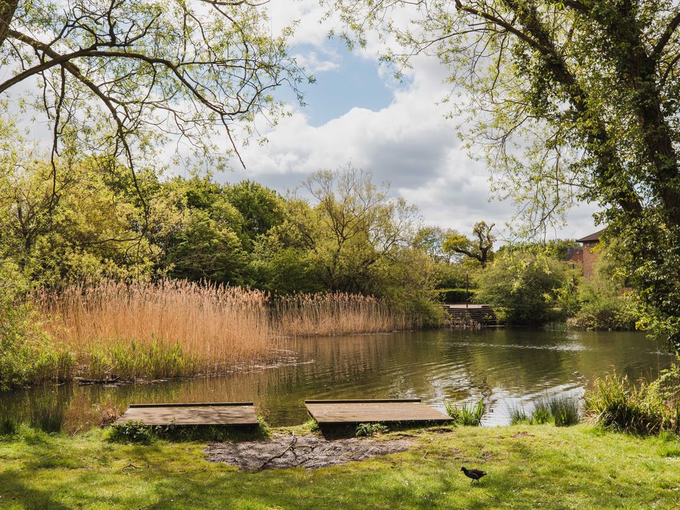 A garden with a pond and wooden platforms at Manor Farm Cottages in Loughton, Milton Keynes