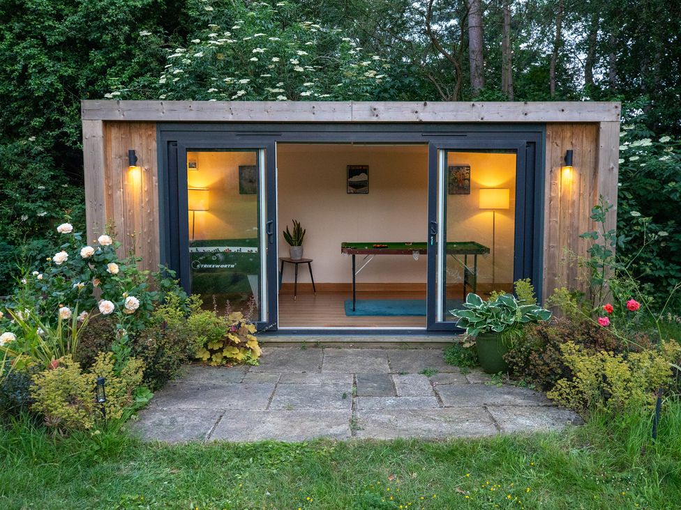 A garden room with a table and lamp at Manor Farm Cottages, Loughton, Milton Keynes