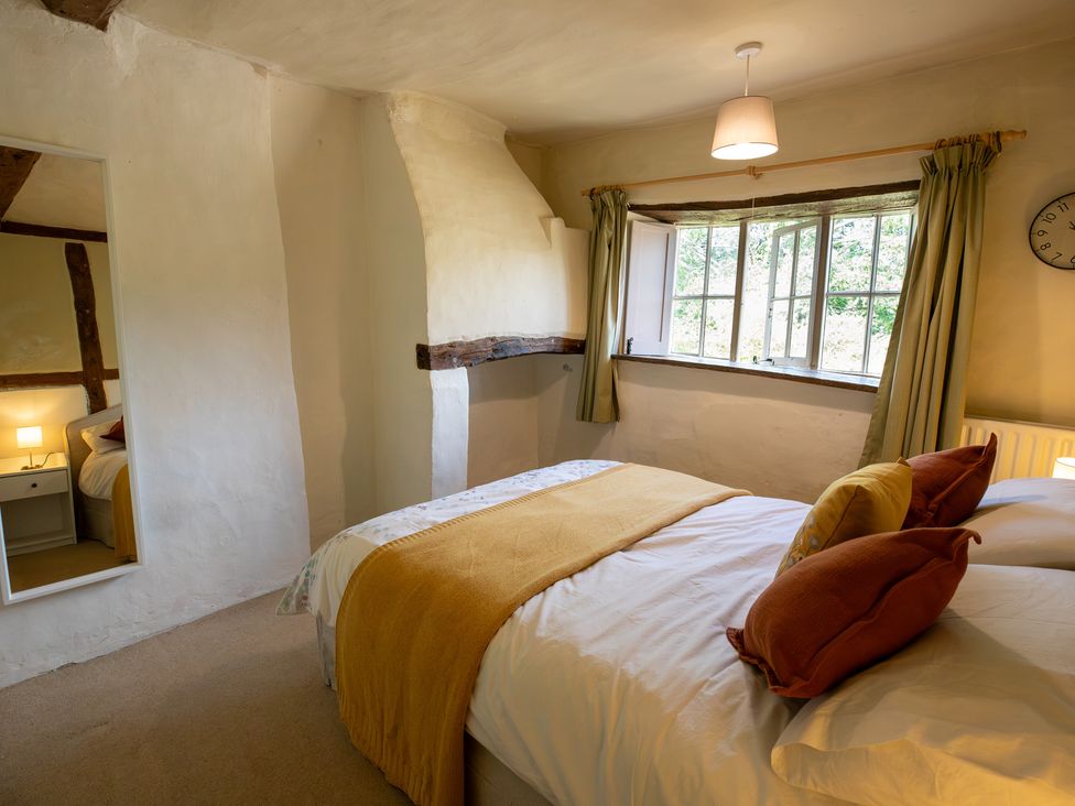 A bedroom with a bed and window at Manor Farm Cottages in Loughton, Milton Keynes