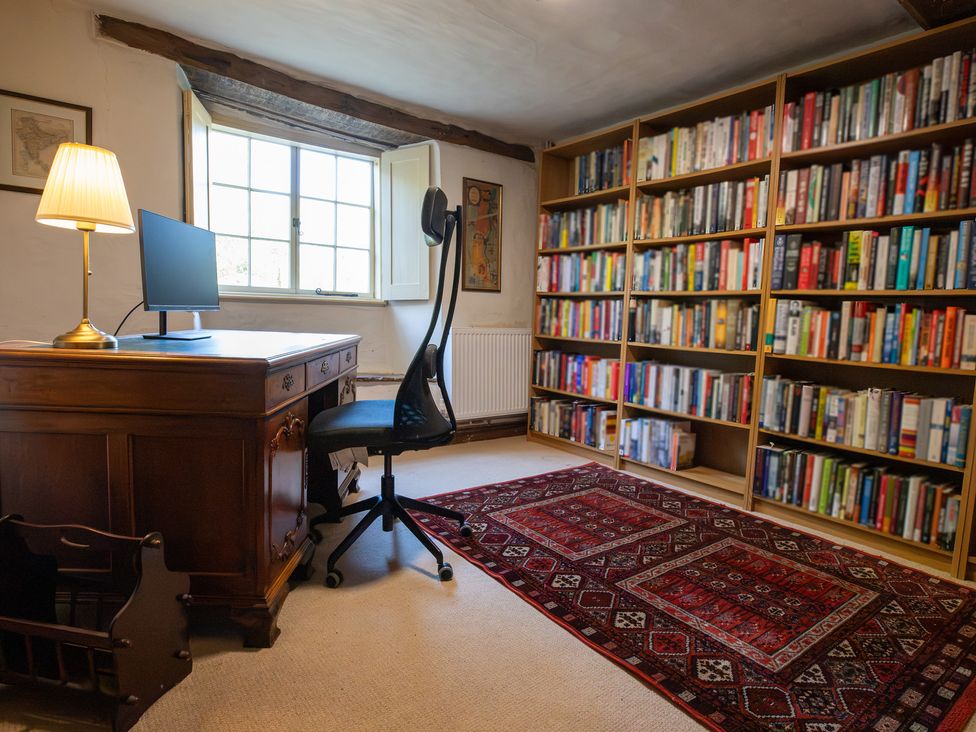 A study with a desk, computer, and bookshelves at Manor Farm Cottages, Loughton, Milton Keynes