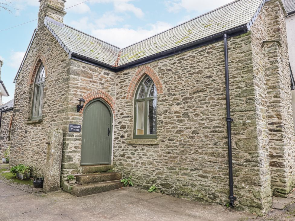 A stone exterior of Flagstaff Cottage with a green door and windows