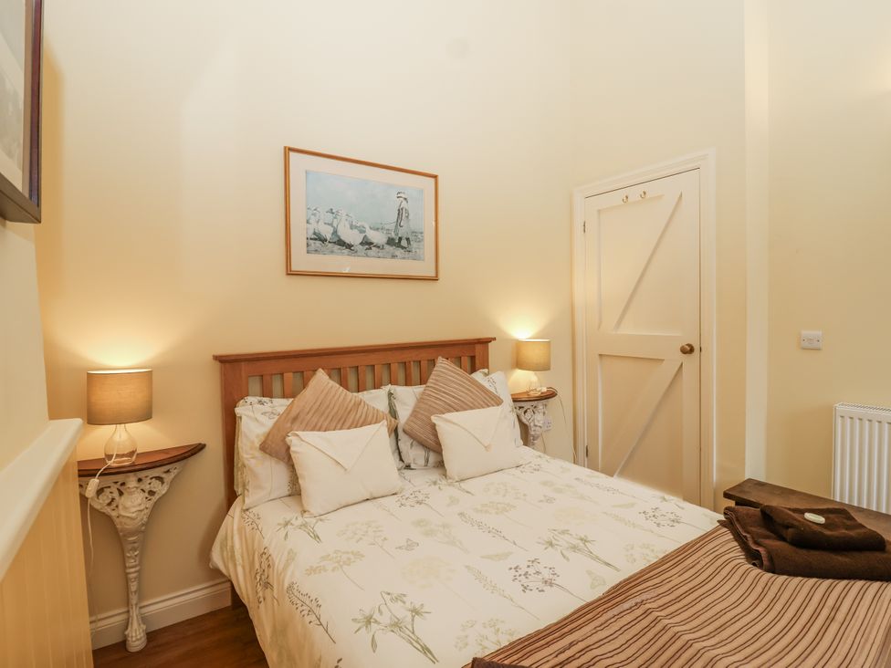 A bedroom with a bed and artwork on the wall at Flagstaff Cottage