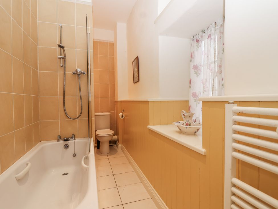 A bathroom with a shower over the bathtub and a toilet at Flagstaff Cottage