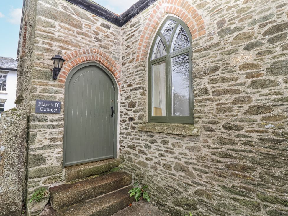An entrance with a stone wall and door at Flagstaff Cottage