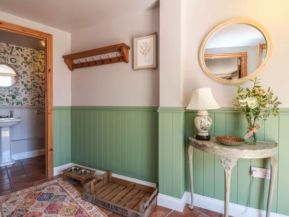 A hallway with a coat rack and sink at Captains Barn in Tiverton