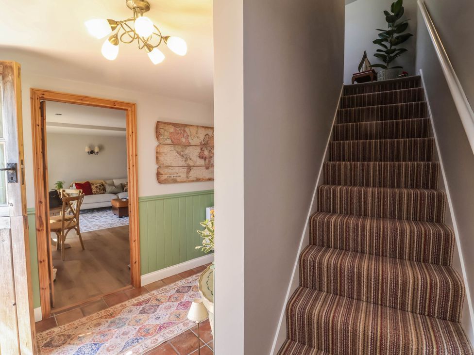 A hallway with a staircase and door at Captains Barn in Tiverton