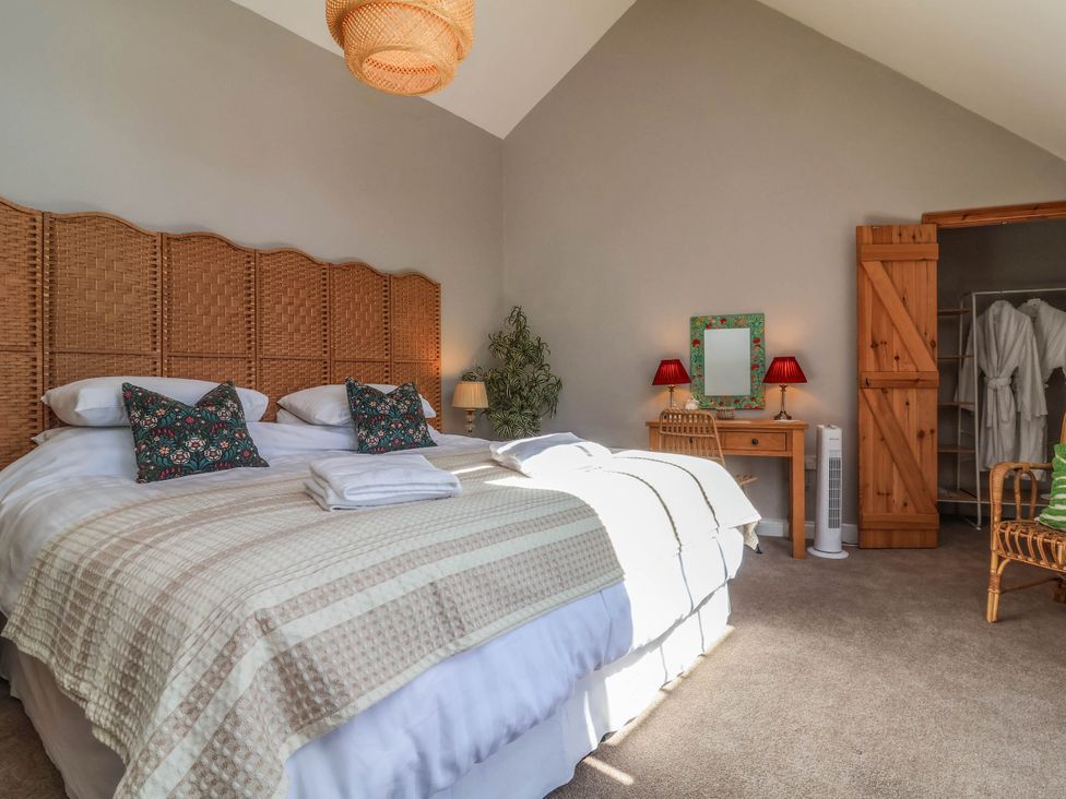 A bedroom with a bed and wardrobe at Captains Barn in Tiverton