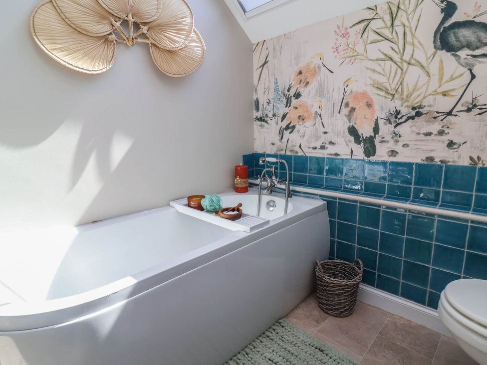 A bathroom with a bathtub and colorful tiles at Captains Barn Tiverton