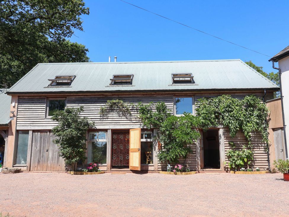 A wooden building with windows and plants at Captains Barn Tiverton