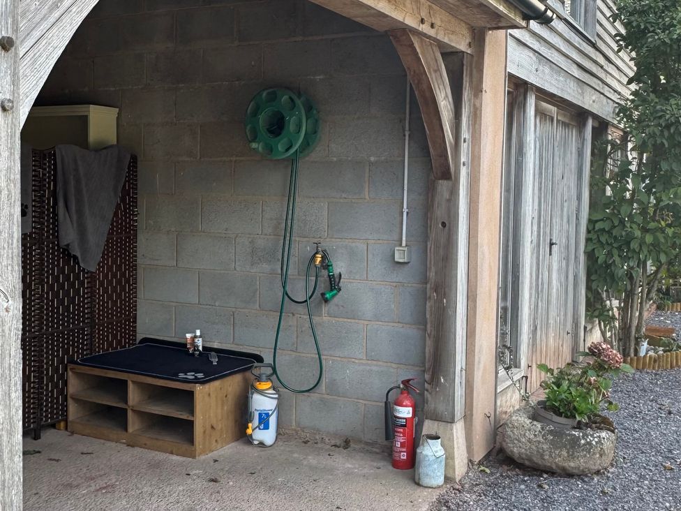 An outdoor area with a hose reel and potted plants at Captains Barn Cadeleigh near Tiverton