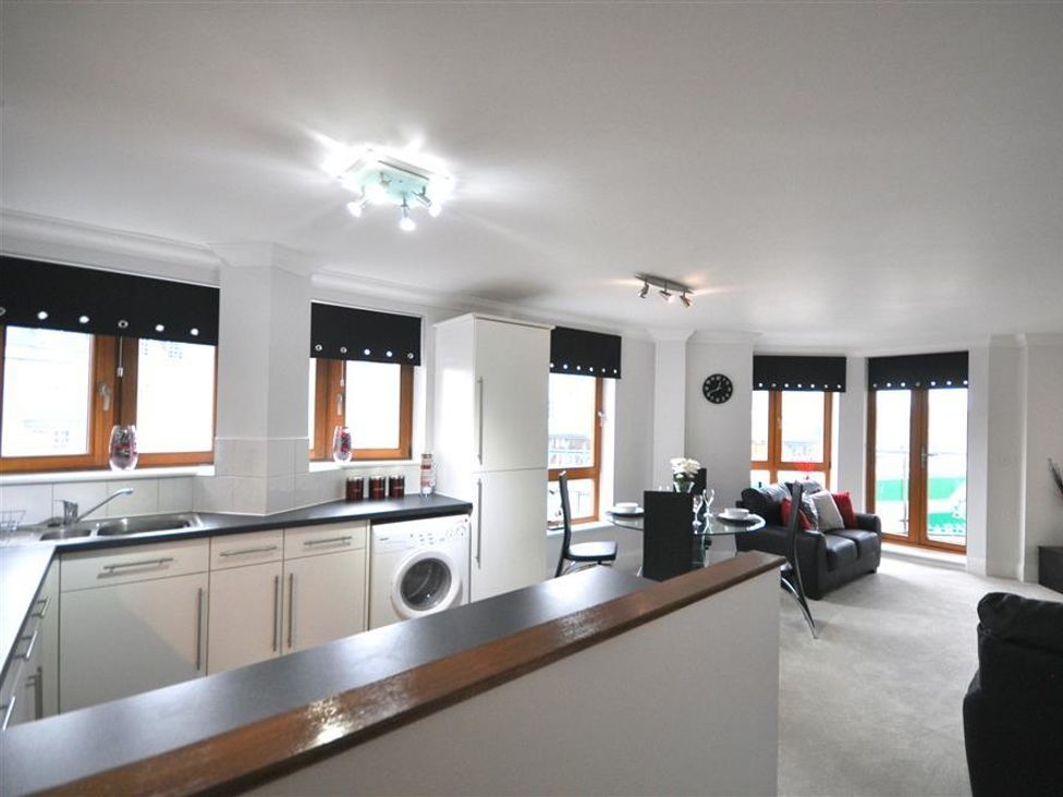 A kitchen and living area with a washing machine and table at Old Harbour View in Weymouth