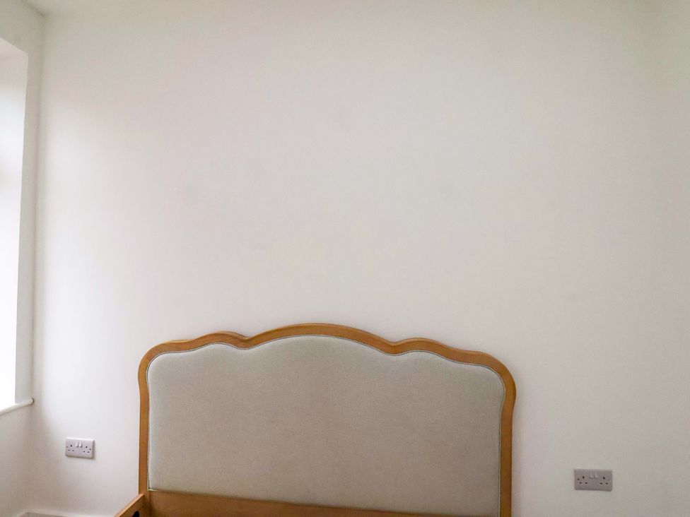 A bedroom with a headboard against a wall at Beachwalk Villa 2 in Whitby