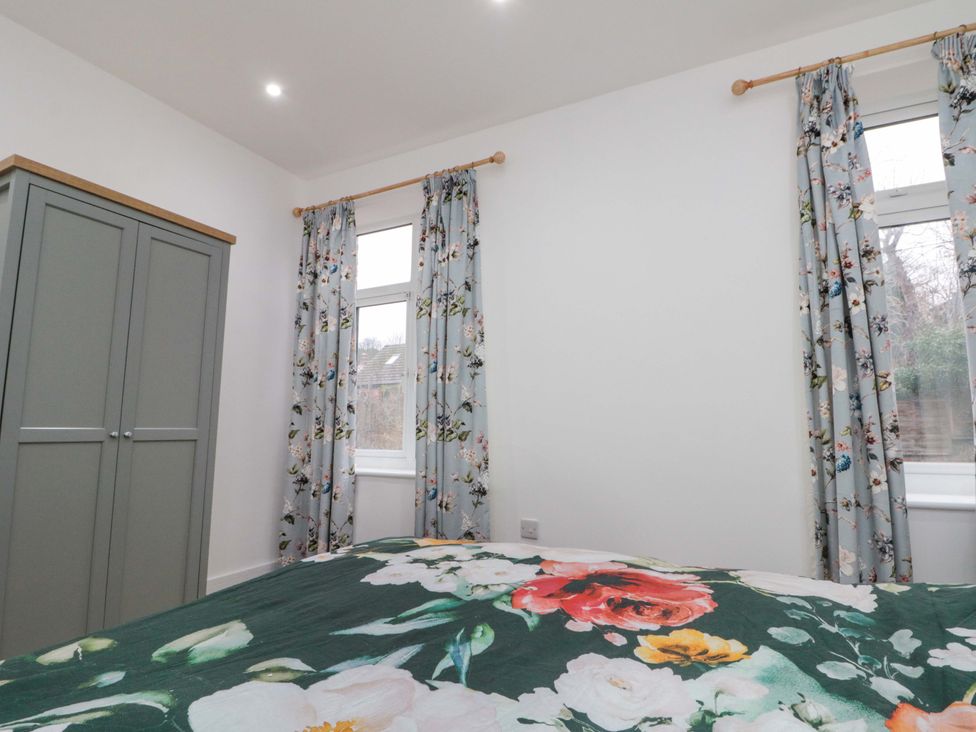 A bedroom with a wardrobe and floral curtains at Beachwalk Villa 2 in Whitby