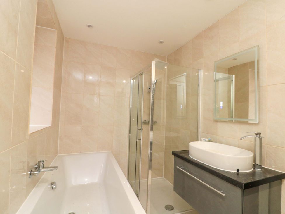 A bathroom with a bathtub, shower, and sink at Beachwalk Villa 2 in Whitby