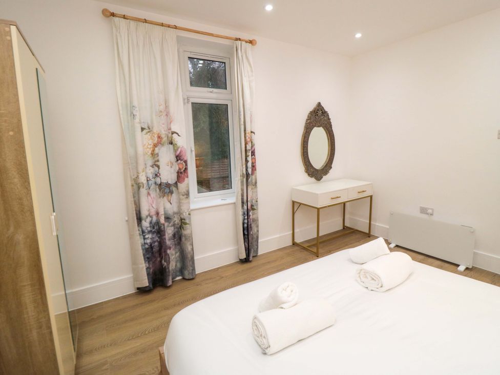 A bedroom with a bed, mirror, and window at Beachwalk Villa 2 in Whitby