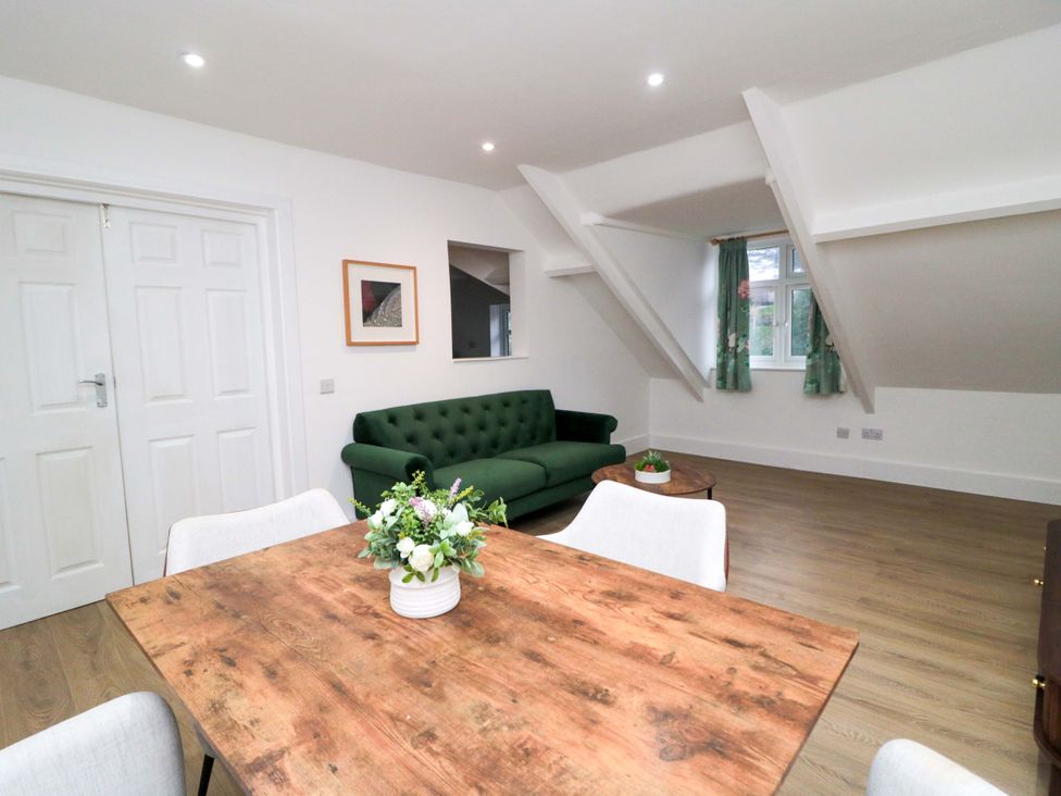 A living room with a green sofa and wooden dining table at Beachwalk Villa 3, Whitby