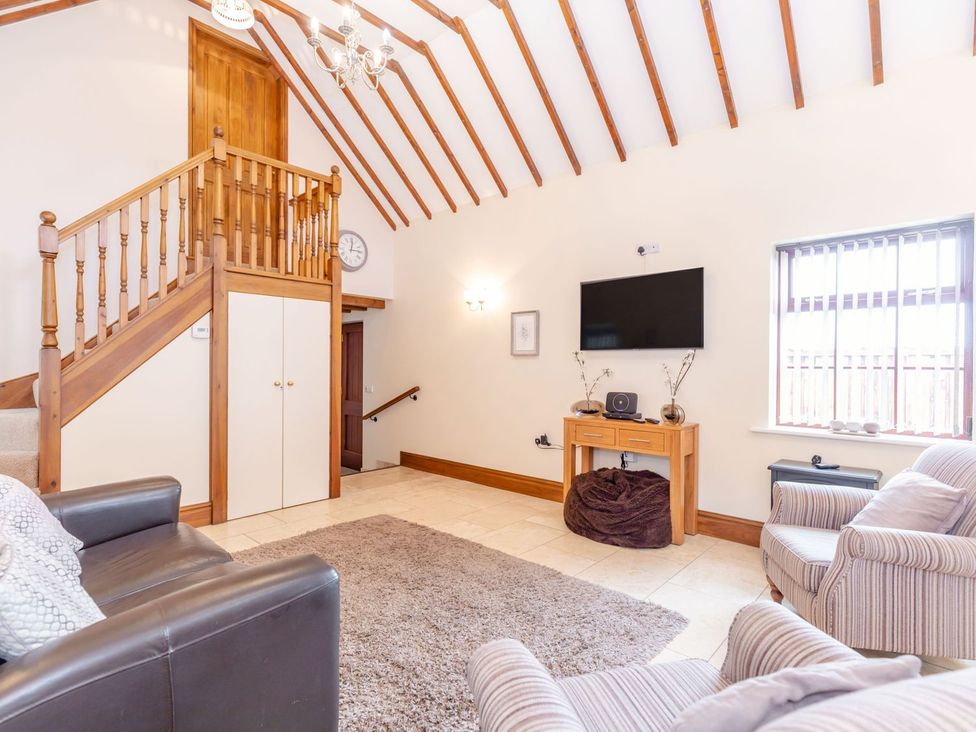 A living room with a staircase and sofa at Lanes Barn in Whitby