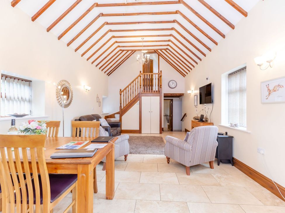 A living room with a dining table and staircase at Lanes Barn in Whitby