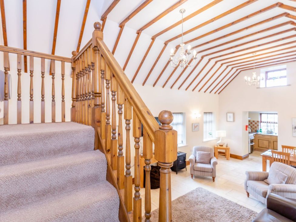 A living room with staircase and kitchen area at Lanes Barn in Whitby