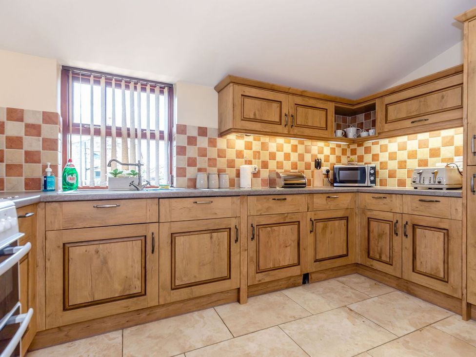 A kitchen with wooden cabinets and appliances at Lanes Barn in Whitby
