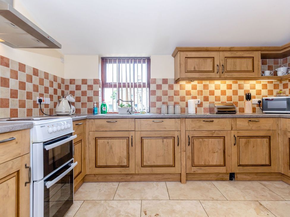 A kitchen with wooden cabinets and appliances at Lanes Barn in Whitby
