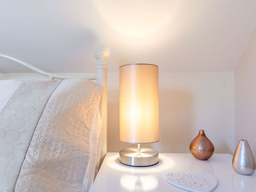 A bedside table with a lamp and decorative items at Lanes Barn in Whitby