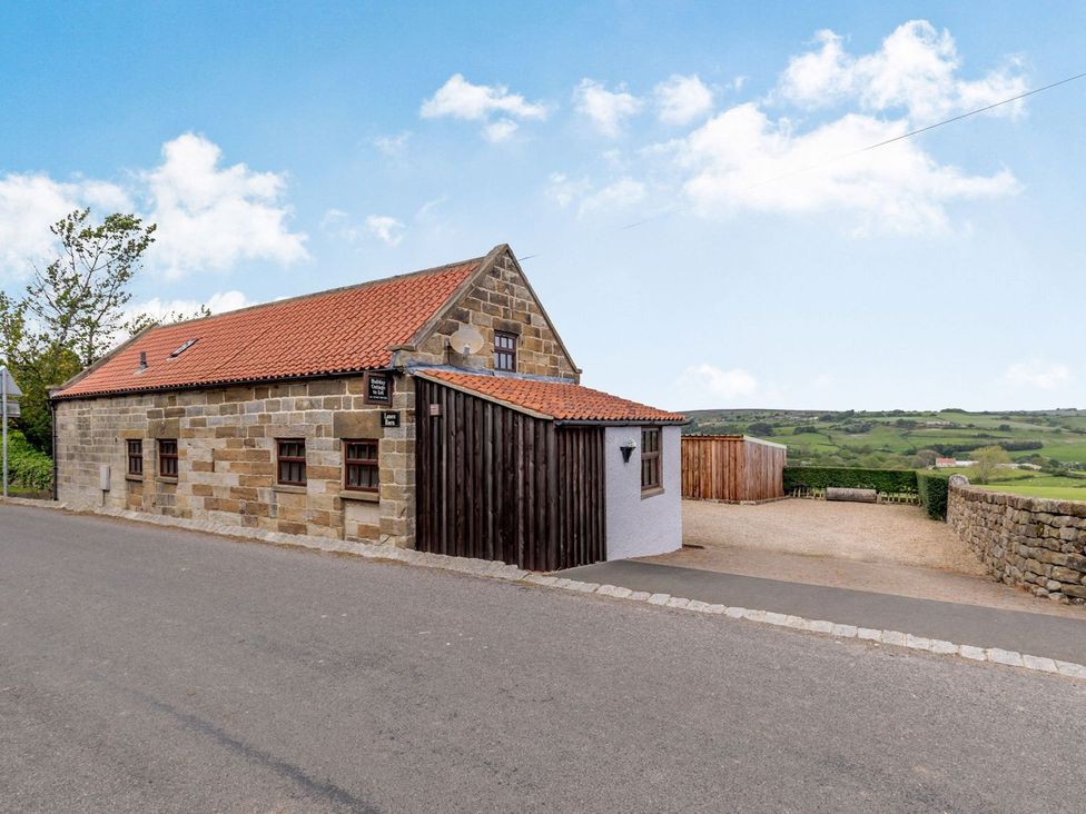 A stone building with a red roof and driveway at Lanes Barn Whitby