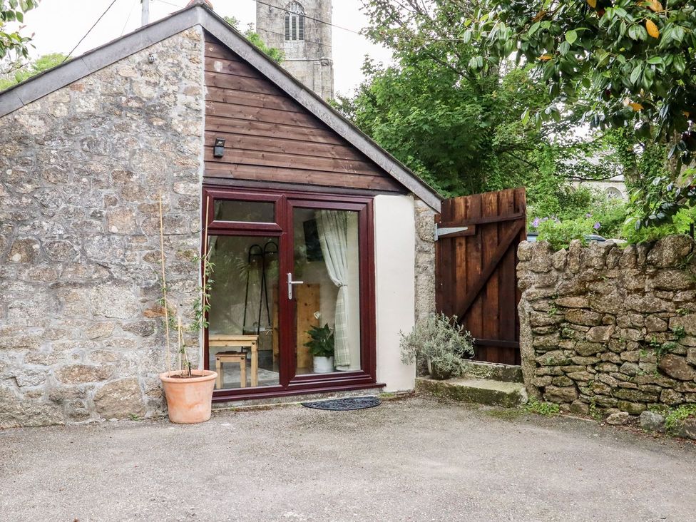 An exterior view of a small building with a door and window at Lannlyvri Lodge in Lanlivery near Lostwithiel