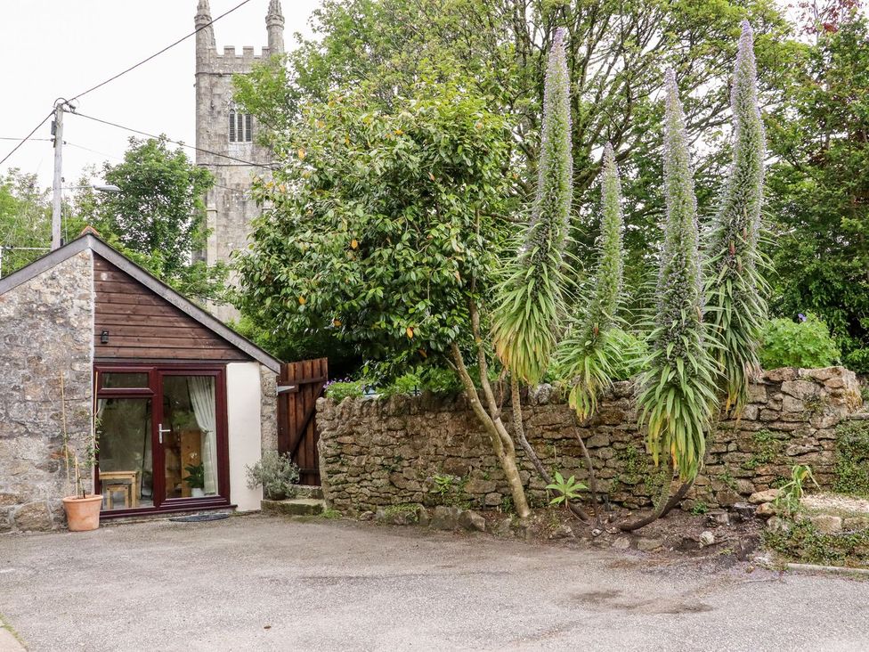 An exterior view of a building with plants and a stone wall at Lannlyvri Lodge in Lanlivery near Lostwithiel