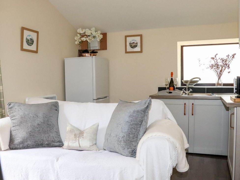 A kitchen with a sofa and refrigerator at Lannlyvri Lodge, Lanlivery near Lostwithiel