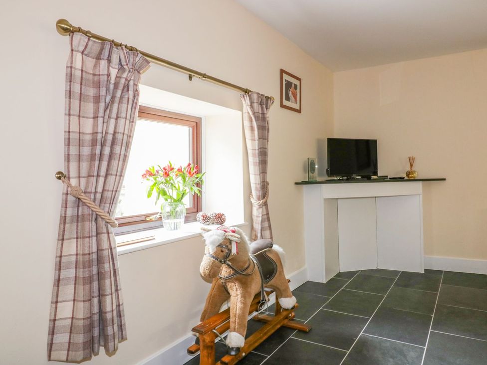 A snug with a rocking horse and television at Camellia Cottage in Bodmin