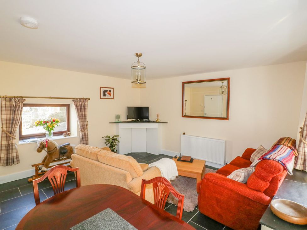 A living room with a sofa and dining table at Camellia Cottage in Bodmin