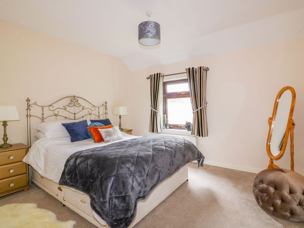 A bedroom with a bed and a dressing mirror at Camellia Cottage in Bodmin