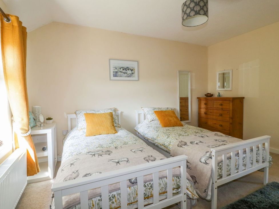 A bedroom with two single beds and a dresser at Camellia Cottage in Bodmin