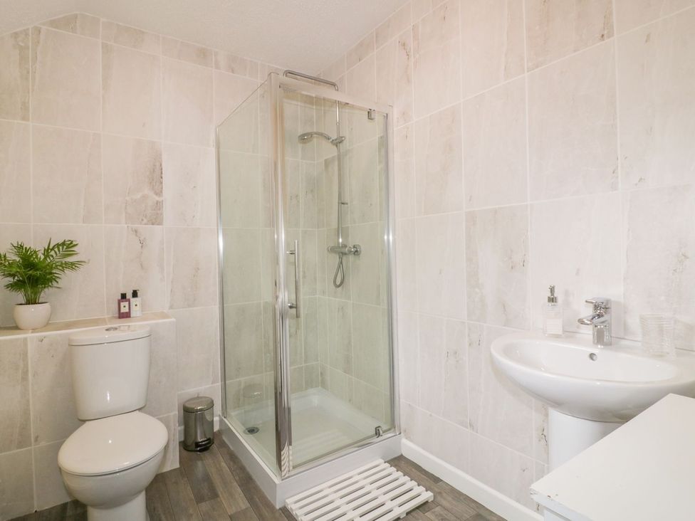 A bathroom with a shower, toilet, and sink at Camellia Cottage in Bodmin