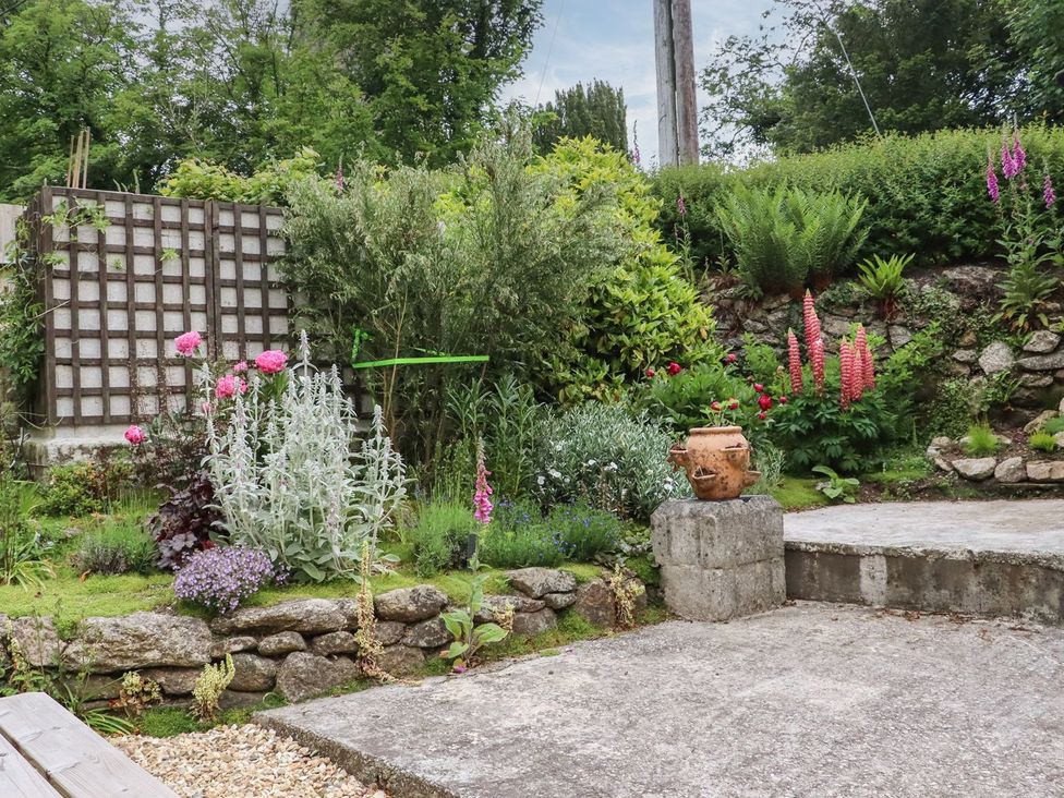 A garden with flowers and stone features at Camellia Cottage in Bodmin