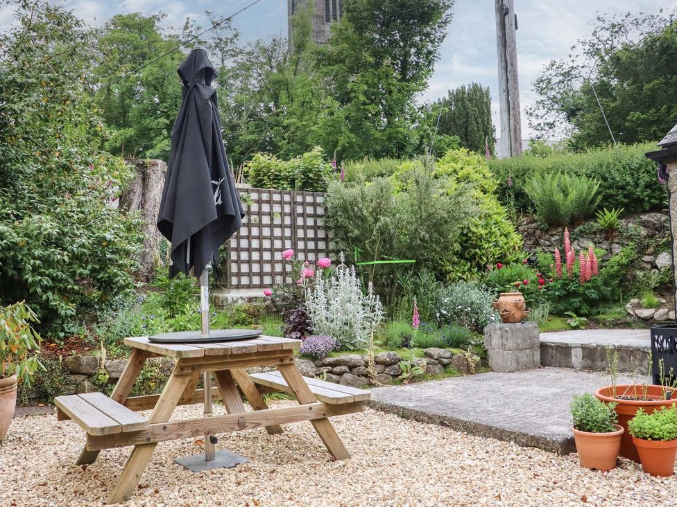 A garden with a wooden table and umbrella at Camellia Cottage Bodmin