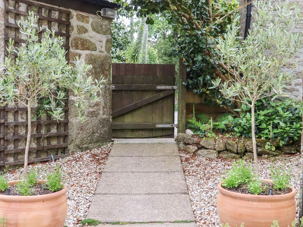 A garden with a stone pathway and potted plants at Camellia Cottage in Bodmin