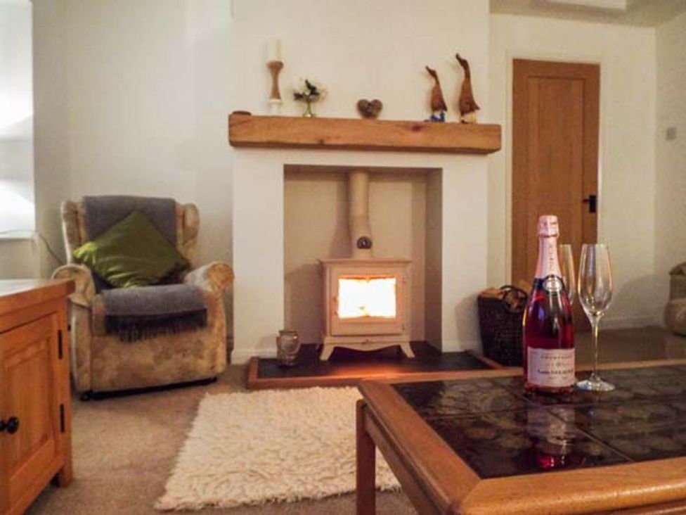 A living room with a fireplace and champagne at Tyddyn Gyrfa Cottage in Cemaes Bay