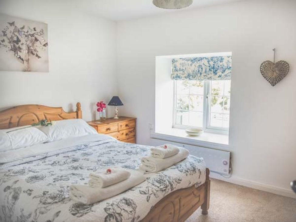 A bedroom with a bed and window at Tyddyn Gyrfa Cottage in Cemaes Bay