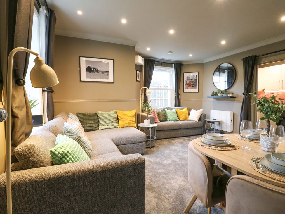 A living room with a sofa and dining area at 1A Coastguard Cottages in Rye