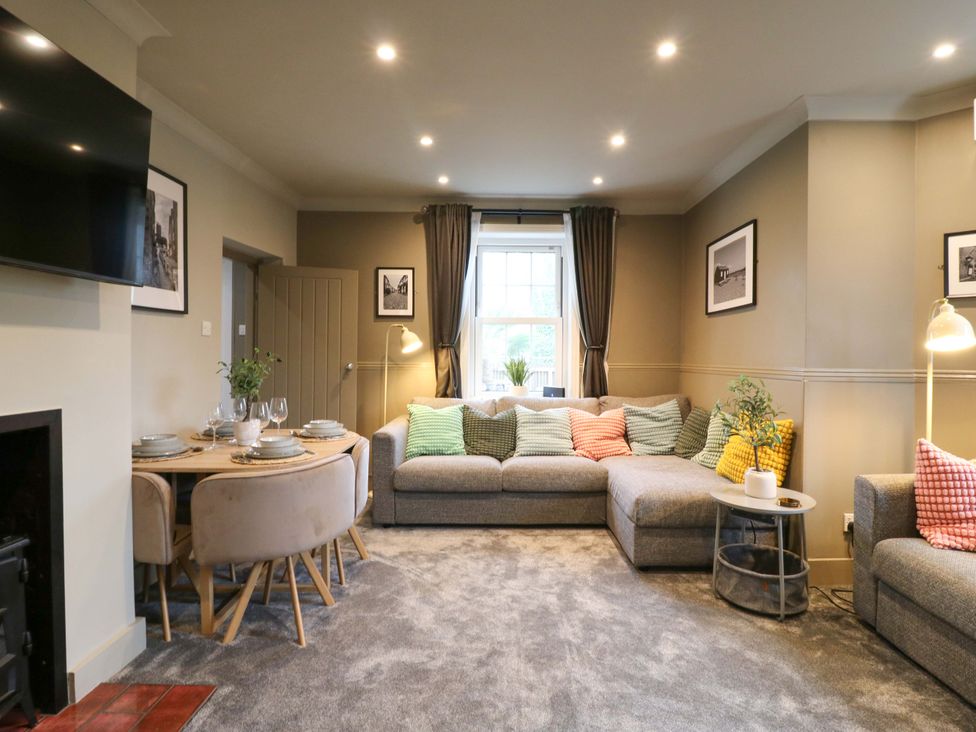 A living room with a sofa and dining area at 1A Coastguard Cottages in Rye