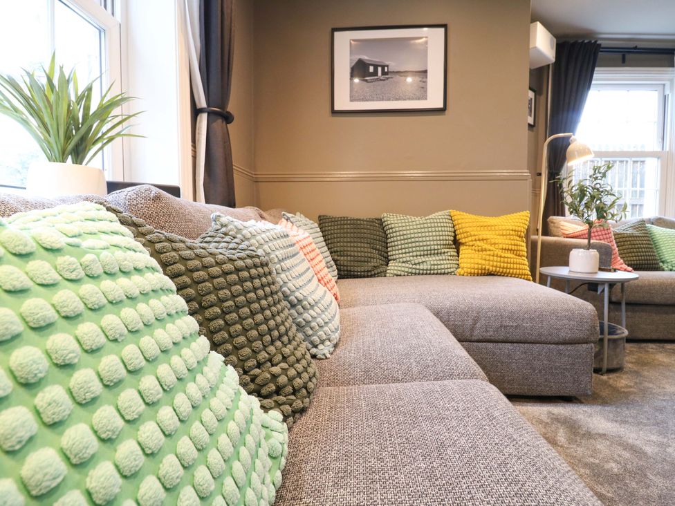 A living room with a couch and pillows at 1A Coastguard Cottages in Rye