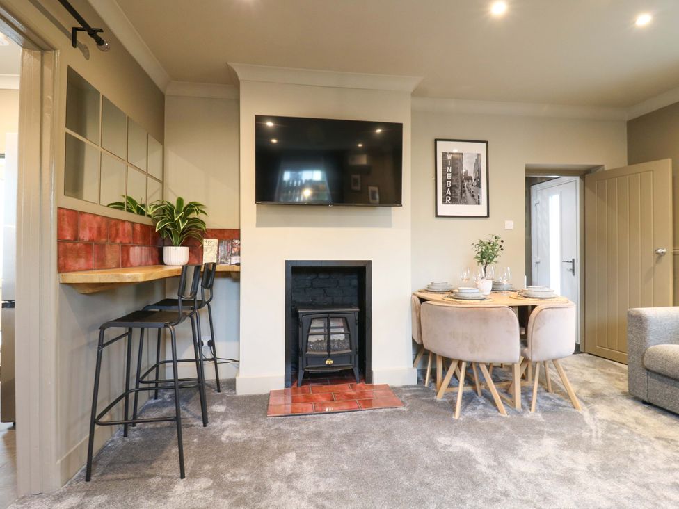 A living room with a fireplace and dining area at 1A Coastguard Cottages in Rye