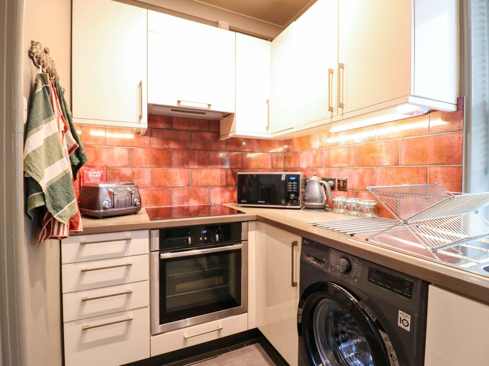 A kitchen with appliances including a oven and washing machine at 1A Coastguard Cottages in Rye