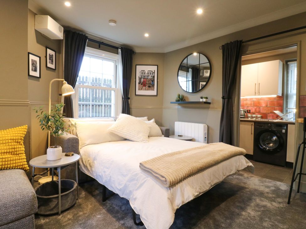 A studio with a bed, couch, kitchenette and window at 1A Coastguard Cottages in Rye