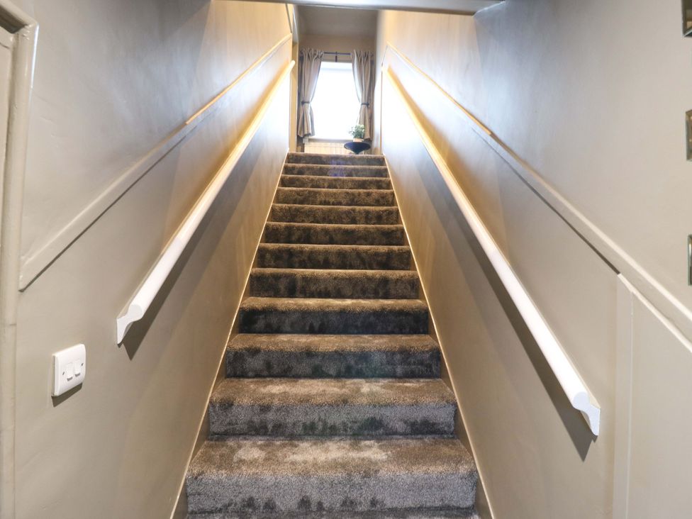 A staircase with carpet and handrail at 1A Coastguard Cottages in Rye
