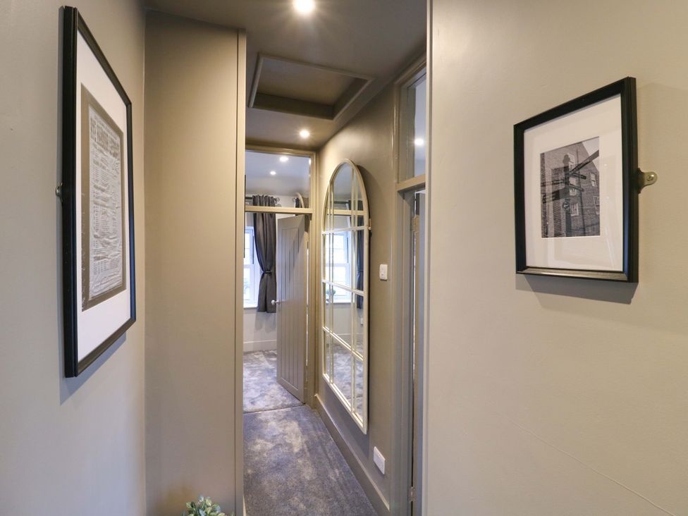A hallway with a mirror and pictures on the wall at 1A Coastguard Cottages in Rye